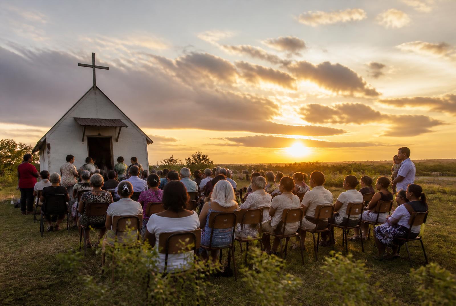 A rural congregation gathered outdoors at sunset